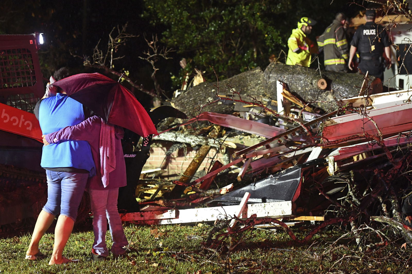 Bystanders hug as first responders work to free a victim after a tree fell on a house Dec. 28 in Natchez