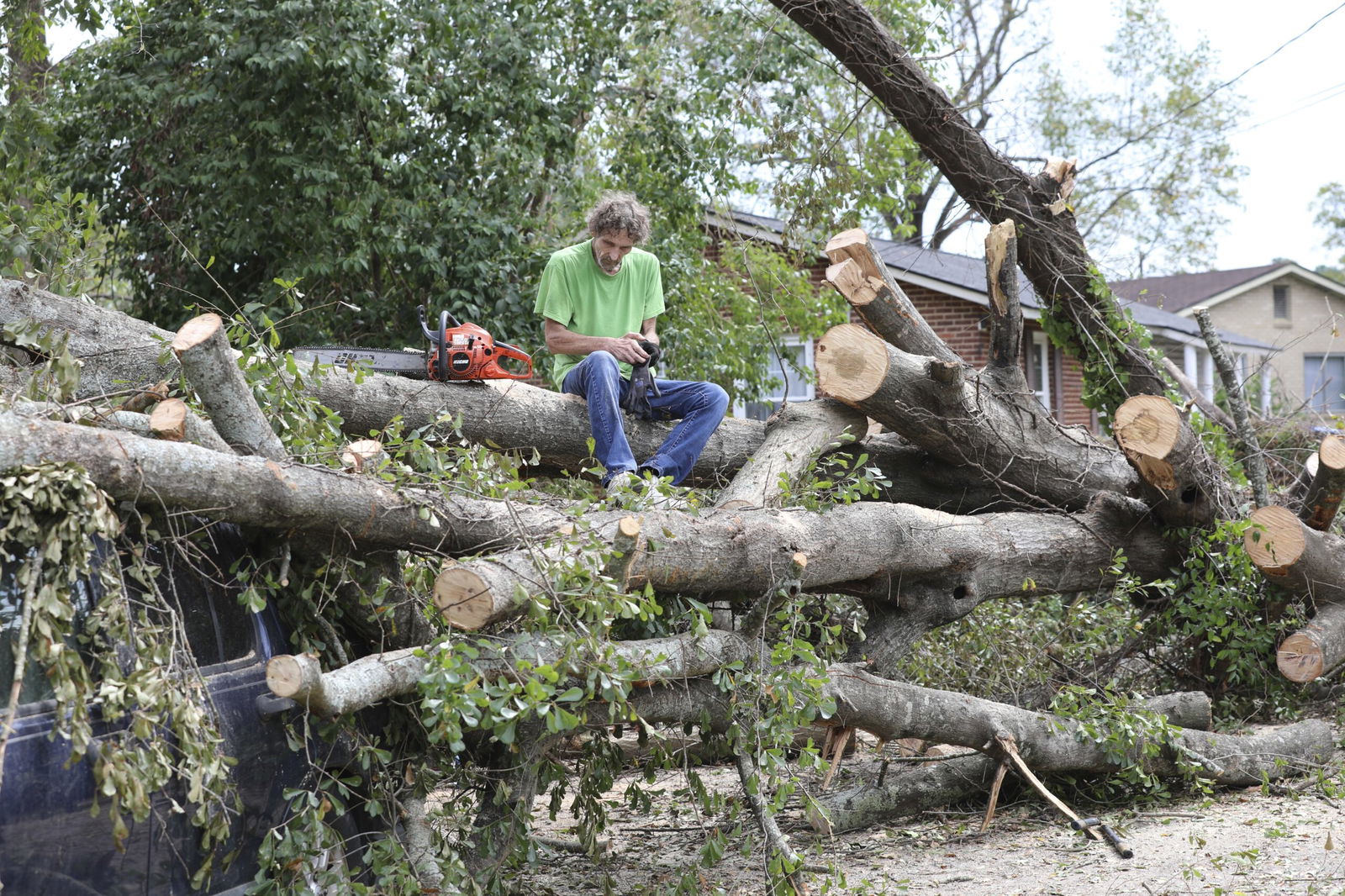Andy Brown takes a break on top of what remains of a tree that destroyed his SUV when it fell during Hurricane Helene on Oct. 1 in Augusta