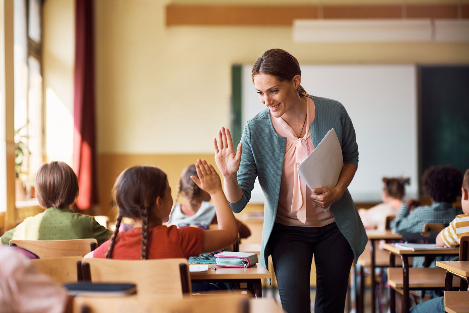 A teacher high fives her students.