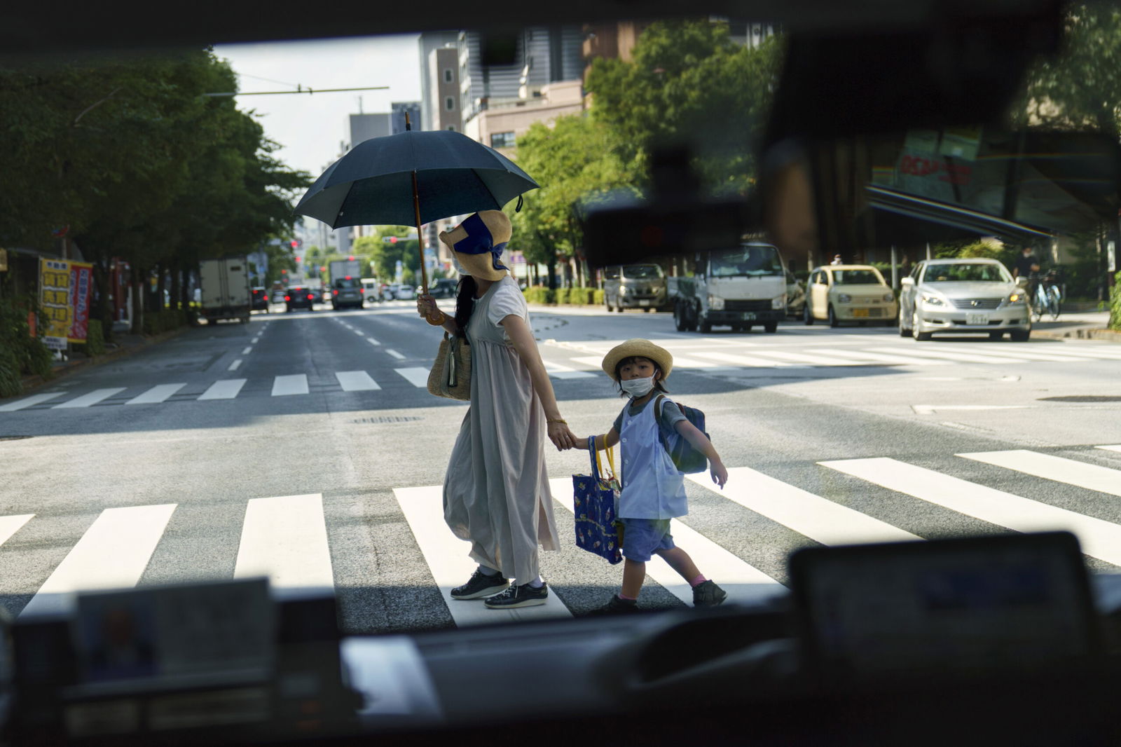 A pedestrian crossing a street with a child is seen through a taxi window in 2021 in Tokyo. Japan’s birth rate fell to a new low for the eight straight year in 2023