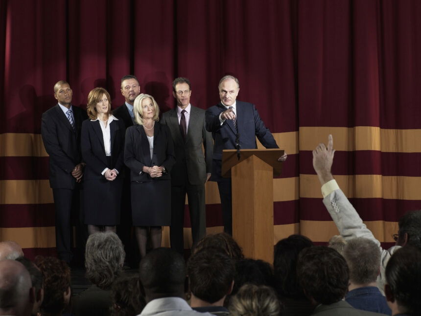 Businessman on stage with colleagues receiving questions from audience