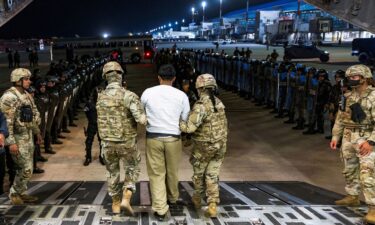 US military personnel escort an alleged gang member who was deported by the US along with others the US alleges are members of the Venezuelan gang Tren de Aragua and the MS-13 gang at the El Salvador International Airport in San Luis Talpa