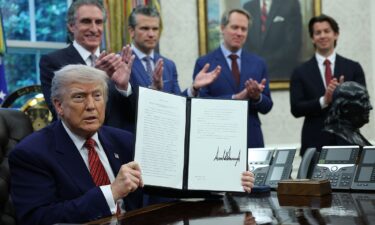 President Donald Trump holds up a signed executive order in the Oval Office of the White House on May 23 in Washington