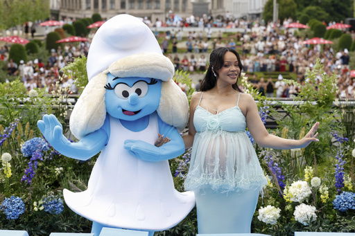 Rihanna poses with a person in a Smurfette costume for photographers upon arrival at the world premiere of the film