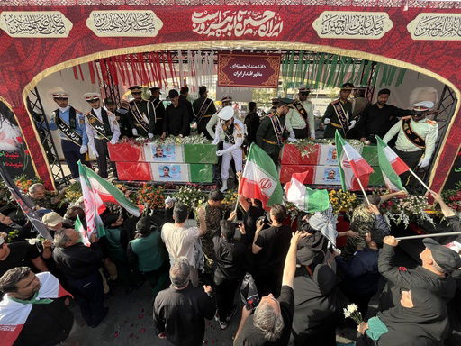 People mourn over the flag-draped coffins of Iranian nuclear scientists who were killed in Israeli strikes