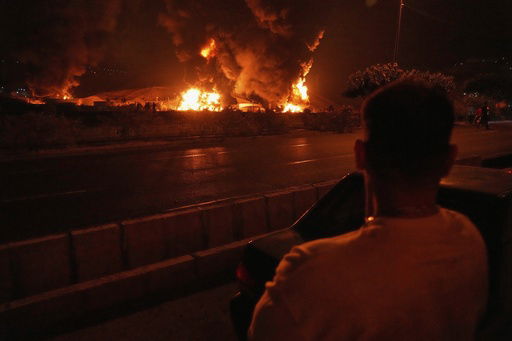 A man looks at flames rising from an oil storage facility after it appeared to have been struck by an Israeli strike in Tehran