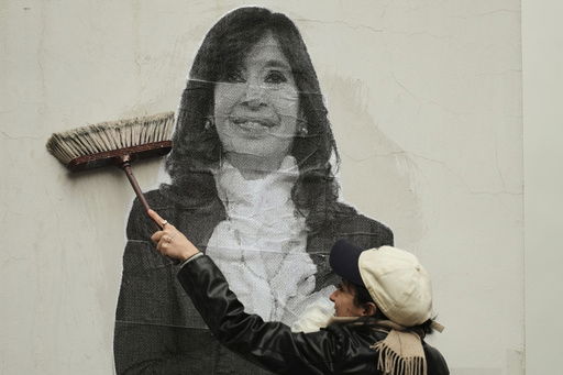 A supporter of Argentina's former President Cristina Fernandez uses a boom to paste a photo of her on the wall outside her home after the nation's Supreme Court upheld Fernandez's corruption conviction in Buenos Aires