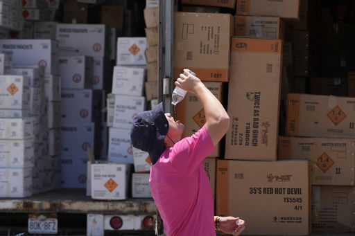 FILE - Wyatt Seymore pours the last drops of liquid from a water bottle into his mouth as he takes a break from unloading a stiflingly hot trailer of fireworks outside Powder Monkey Fireworks ahead of the opening of the stand