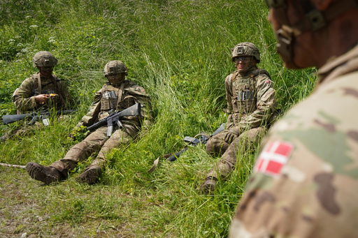 Young conscripts sit waiting in the grass during final exercises at a training area close to Royal Danish Army’s barracks in Hovelte