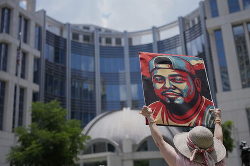 Katheryn Millwee holds a portrait of Kilmar Abrego Garcia outside the federal courthouse Wednesday