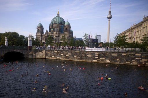 People swim in the river Spree to demand the lift of the hundred years old swimming ban at the river in front of the Berlin Cathedral and the TV Tower in Berlin