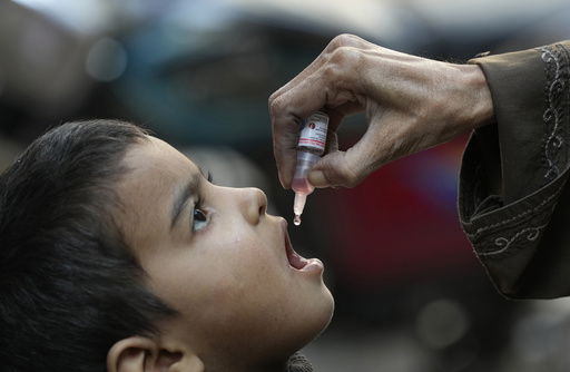 FILE - A health worker administers a polio vaccine to a child in Karachi