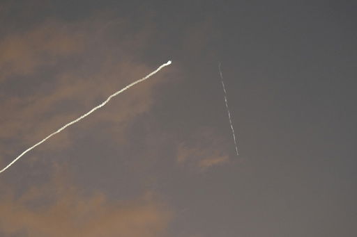 A smoke trail from the Israeli Iron Dome air defense system streaks across the sky as it intercepts missiles launched during an Iranian attack