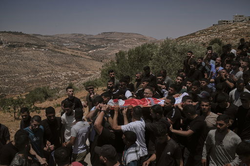 Mourners carry the bodies of three Palestinians who were killed on Wednesday when Jewish settlers stormed the West Bank village of Kafr Malik