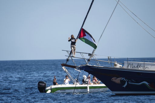 Climate activist Greta Thunberg stands near a Palestinian flag after boarding the Madleen boat and before setting sail for Gaza along with activists of the Freedom Flotilla Coalition