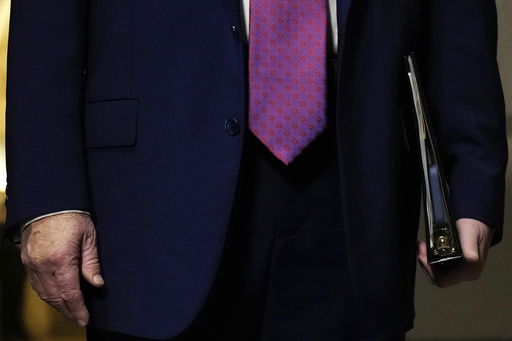 FILE - President Donald Trump holds a binder with a cell phone inside while speaking to reporters before a House Republican conference meeting