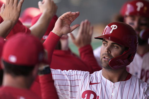 FILE - Philadelphia Phillies' Whit Merrifield celebrates with teammates after scoring during the fourth inning of a spring training baseball game against the Atlanta Braves