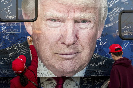 FILE - Supporters of Republican presidential nominee former President Donald Trump sign a bus before a campaign rally at the Butler Farm Show