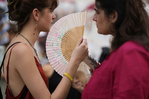 Demonstrators use fans to help with the high temperature during a protest against the housing crisis affecting Portugal