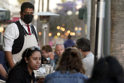 FILE - A server tends to customers in an outdoor dining area on The Promenade in Santa Monica