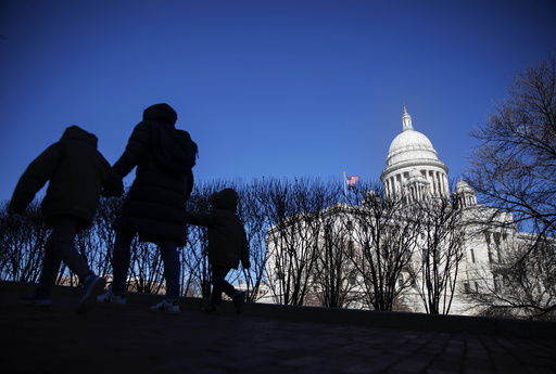 FILE - Pedestrians walk past the Rhode Island Statehouse on March 1