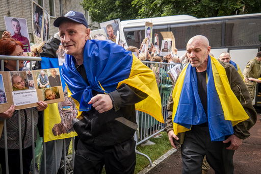 Freed Ukrainian soldiers arriving after a POW exchange with Russia walk past Ukrainians holding photos of their missing relatives in the Chernyhiv region