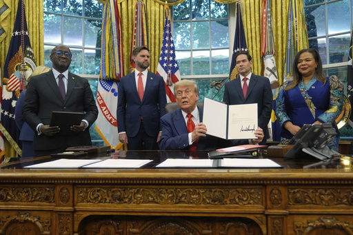 President Donald Trump holds up a signed document to present to Congo's Foreign Minister Therese Kayikwamba Wagner