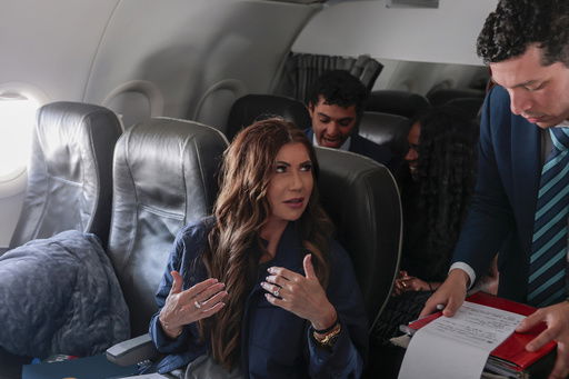 U.S. Homeland Security Secretary Kristi Noem reviews notes with staff member Steven Munoz on a plane to Joint Base Andrews