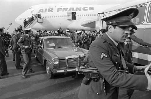 FILE - Ayatollah Ruhollah Khomeini has a heavy escort as he enters car to leave the airport in Tehran