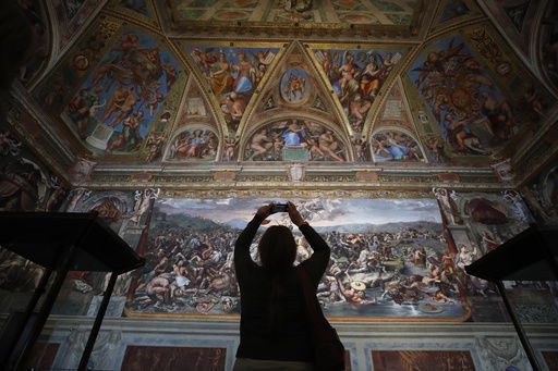 FILE - A visitor admires a Raphael Room inside the Vatican Museums at the Vatican