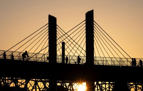 Poeple walk across the Big Four Bridge as the sun sets at Waterfront Park on June 22 in Louisville