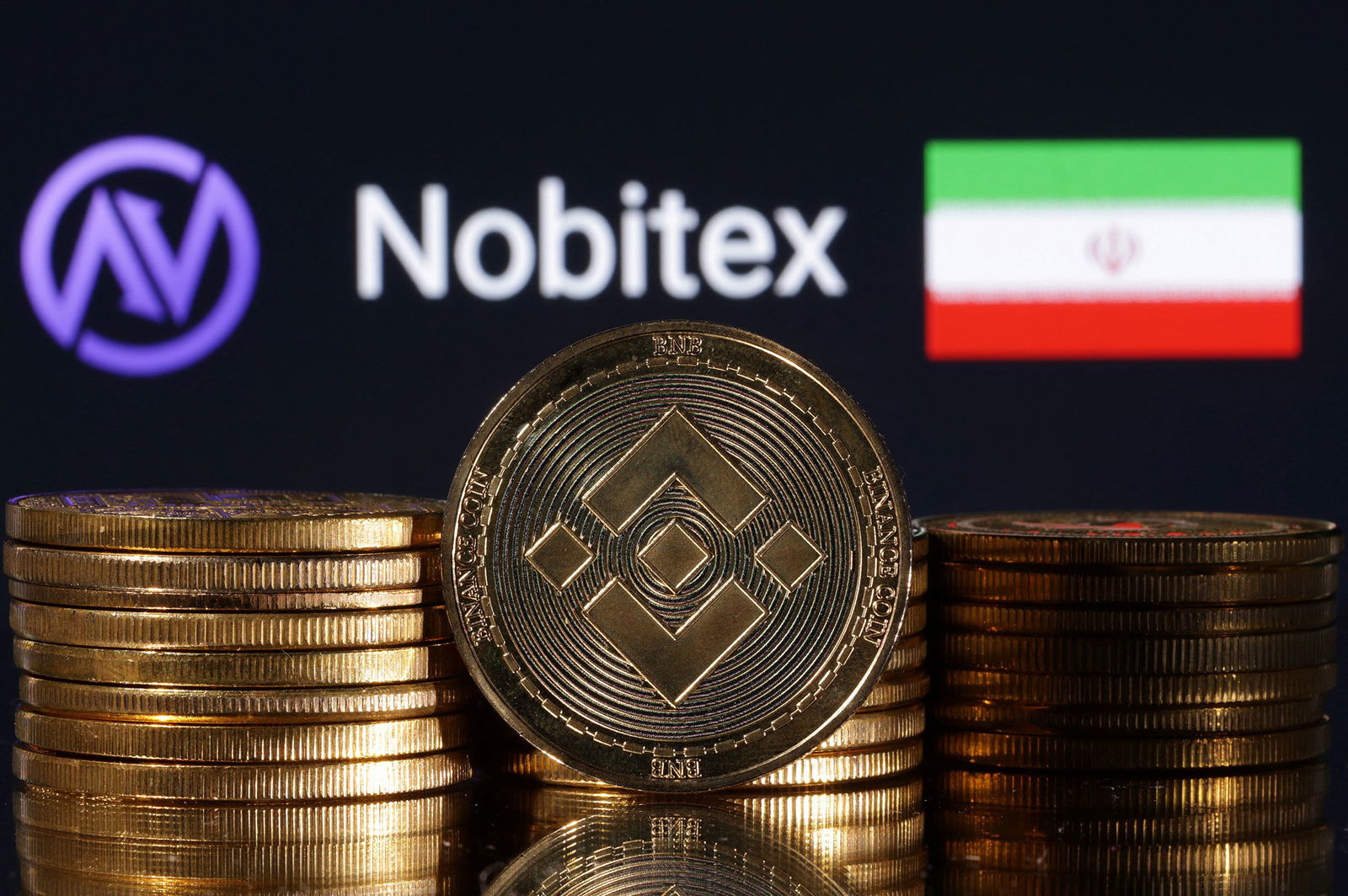 <i>Dado Ruvic/Reuters via CNN Newsource</i><br/>Representations of cryptocurrency Binance are seen in front of displayed Nobitex logo and Iran flag in this illustration taken in November 2022.