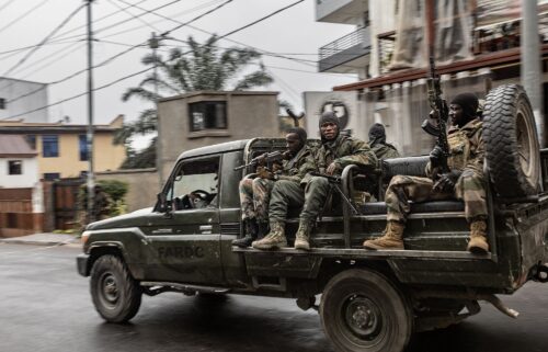 Congolese families displaced by ongoing clashes in eastern Democratic Republic of Congo line up as they wait for Rwandan police and immigration officials to allow them to return to the country