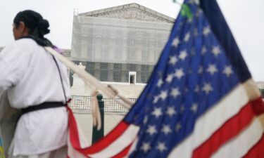 A person stands with a US flag attached to them