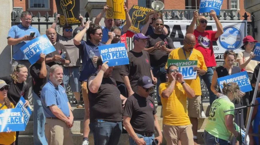 <i>WBZ via CNN Newsource</i><br/>Uber and Lyft drivers rally against driverless taxis outside Massachusetts State House.