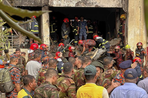 Firemen check the wreckage of a Bangladesh Air Force training aircraft that crashed onto a school campus in Dhaka
