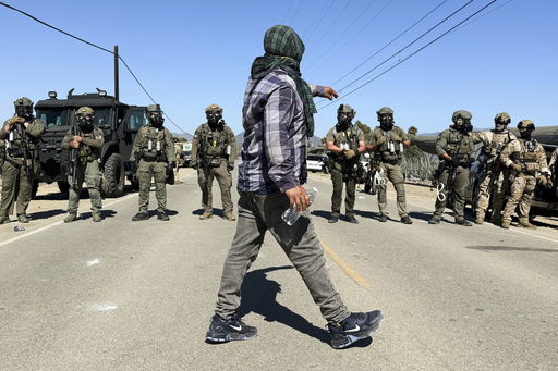 A demonstrator walks in front of federal agents blocking a road during an immigration raid in Camarillo
