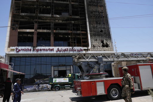 Firefighters gather in front of a burning hypermarket building in Kut