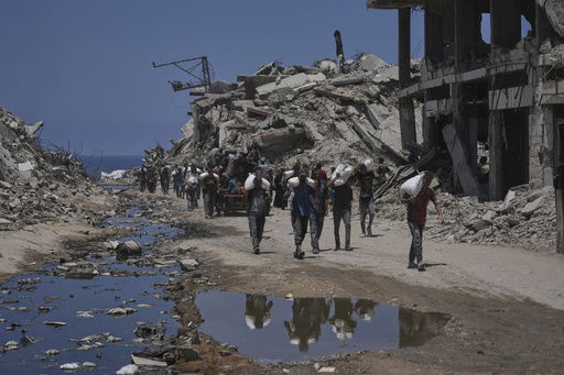 Palestinians carry sacks of flour unloaded from a humanitarian aid convoy that reached Gaza City from the northern Gaza Strip