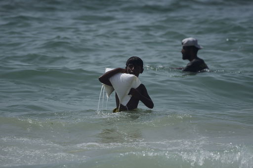 A Palestinian youth carries a sack of aid that landed in the Mediterranean Sea after being airdropped over central Gaza