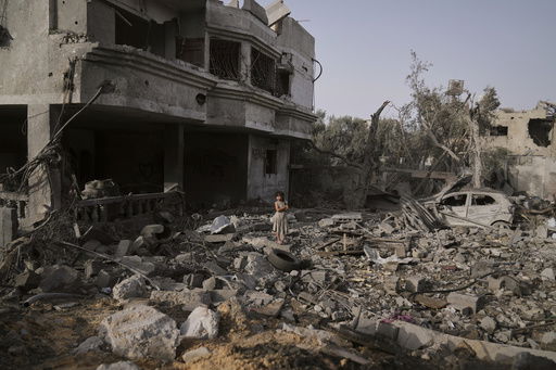 A Palestinian girl stands atop the rubble of the Al-Aimawi family's home that was destroyed by Israeli airstrikes in Al-Zawaideh