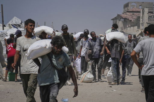 Palestinians carry sacks of flour unloaded from a humanitarian aid convoy that reached Gaza City from the northern Gaza Strip