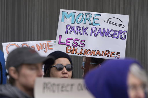 FILE - People hold signs during a protest outside the annual Alaska Sustainable Energy Conference