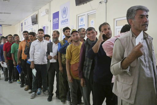 Afghan refugees who returned after fleeing Iran to escape deportation and conflict line up at a UNHCR facility near the Islam Qala crossing in western Herat province