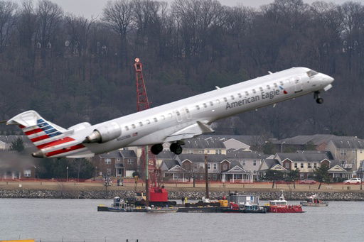 FILE - Salvage crews work on recovering wreckage near the site in the Potomac River of a mid-air collision between an American Airlines jet and a Black Hawk helicopter at Ronald Reagan Washington National Airport