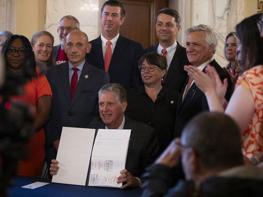 Rhode Island Gov. Dan McKee presents a signed bill that bans the sale of assault-style weapons in the state of Rhode Island at the Rhode Island Statehouse in Providence