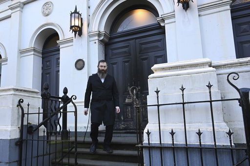Rabbi Dovid Gutnick walks past damage to the exterior of the East Melbourne Hebrew Congregation in Melbourne