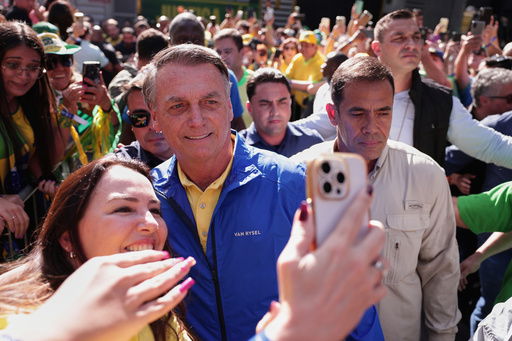 Former President Jair Bolsonaro poses for a selfie with a supporter upon arriving at a protest against his Supreme Court trial