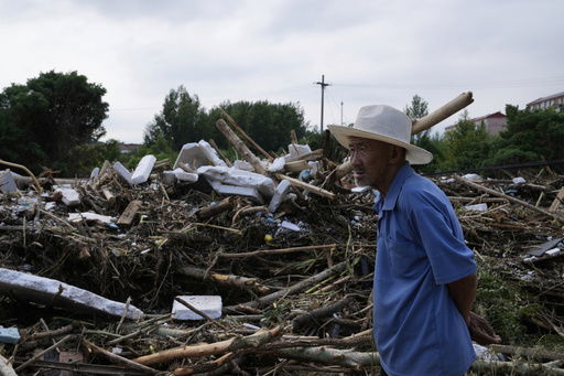 A man looking at a damaged road littered with broken tree branches after a heavy rains in Taishitun Town