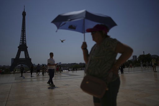 FILE - People walk at Trocadero plaza near the Eiffel Tower during a heat wave July 2